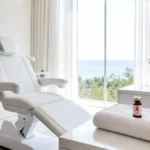 ¿Se puede hacer un injerto capilar con VIH? Sala de valoración premium en Clínica Frontela Huelva con vial médico y lazo rojo simbolizando conciencia del VIH sobre toalla blanca para la evaluación capilar de pacientes seropositivos